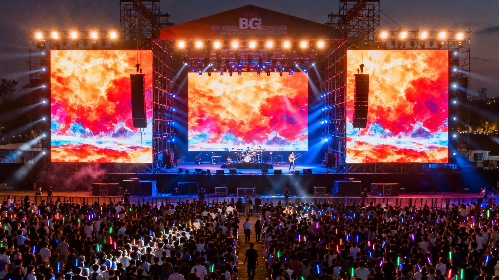 大型户外音乐节现场，主舞台后方搭建了由BG视讯提供的巨型LED租赁屏组，屏幕呈现震撼的视觉效果，舞台灯光与屏幕内容交相辉映，数万名观众沉浸在视听盛宴中